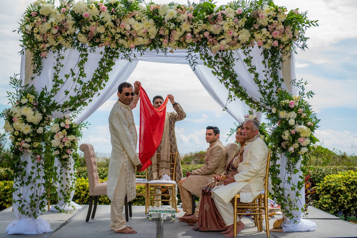 Indian bride and groom at the beach mandap ceremony as the antarpat veil drops