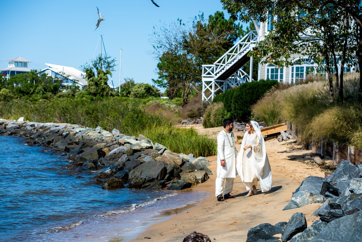 Newlywed couple walking along the shoreline after their nikkah at Chesapeake Bay Beach Club