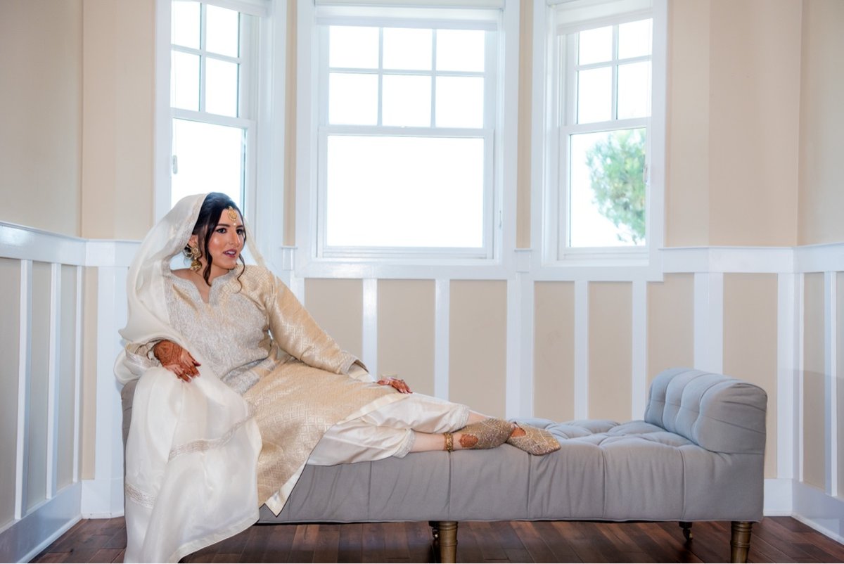 Muslim bride getting ready on a chaise in soft window light at Chesapeake Bay Beach Club Maryland wedding