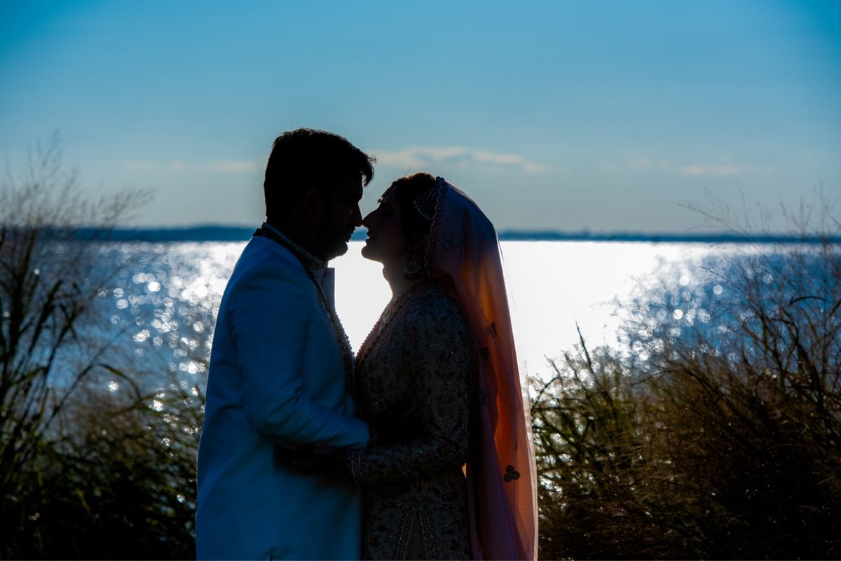 Silhouette of a newlywed couple against the sunset sky over Chesapeake Bay